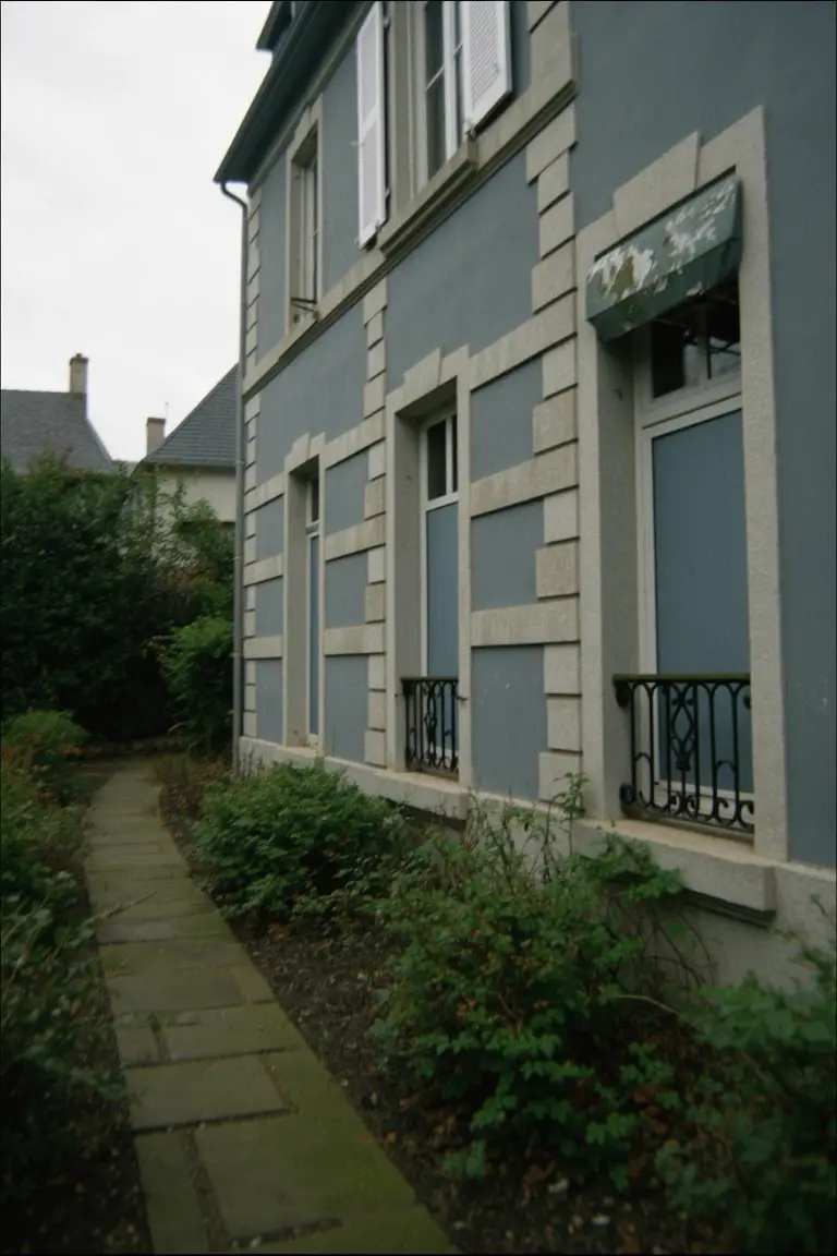 Light blue-gray house exterior with stone accents, shutters, and a stone garden path