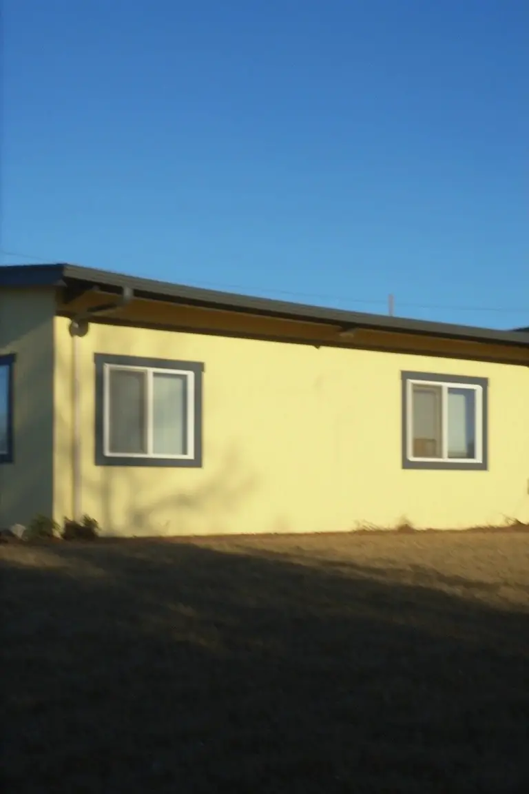Pale yellow house exterior with crisp black window frames and roof trim