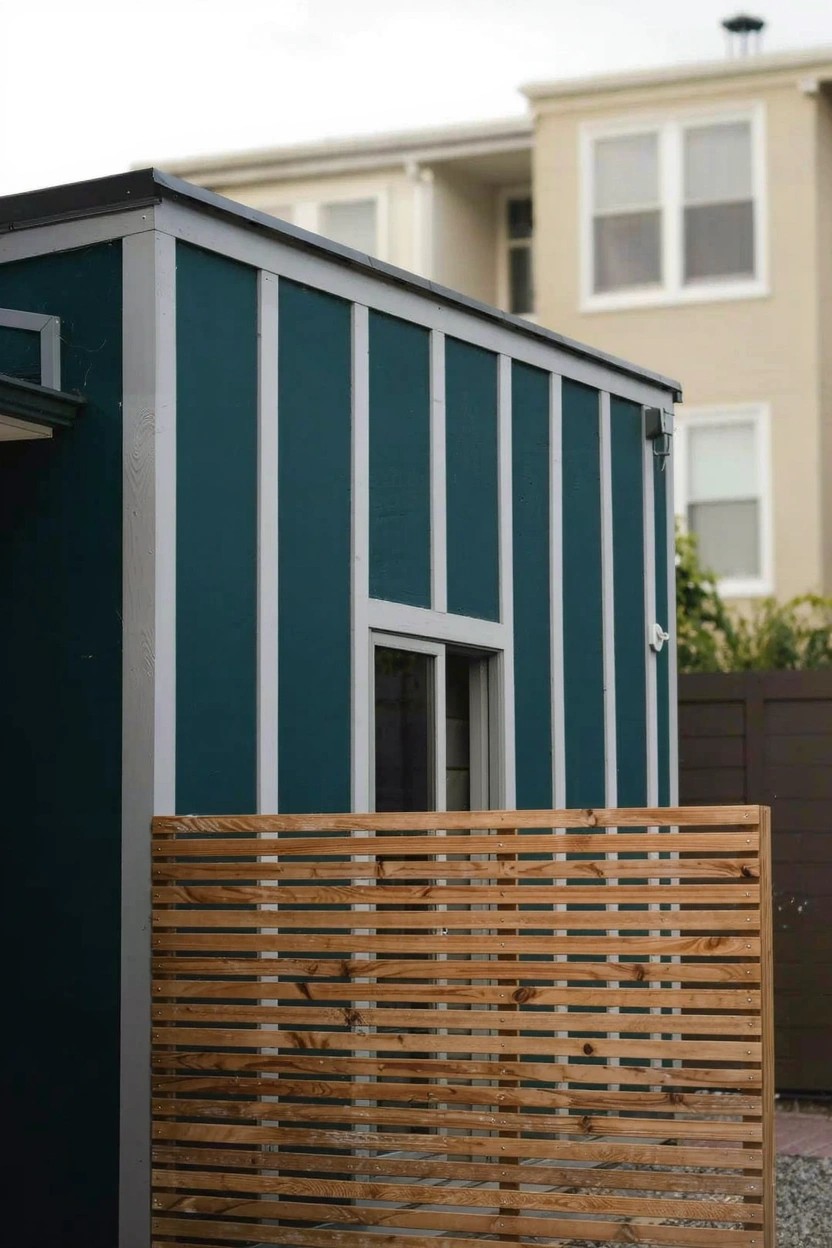 Backyard shed with deep teal siding and slatted wood fence