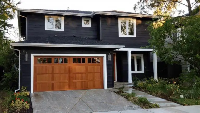 Modern two-story house with deep black siding, white trim, and wood garage door