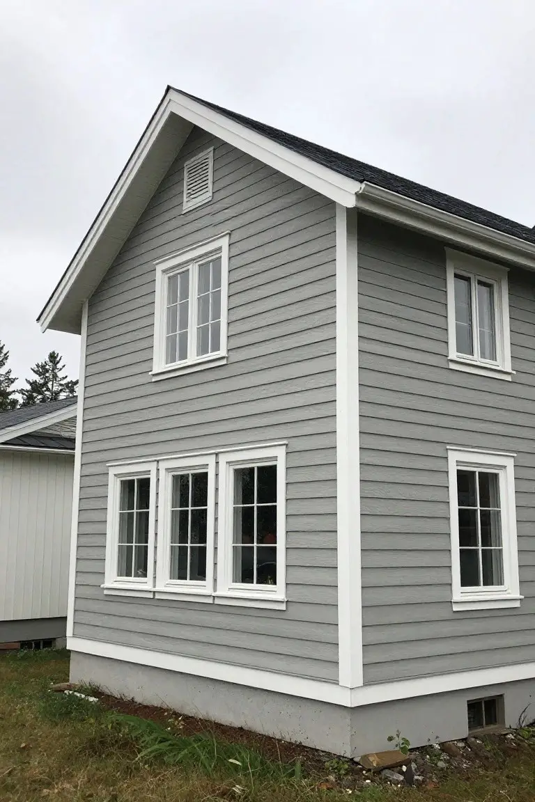 Two-story house with cool light gray clapboard siding, white corner trim, and black roof