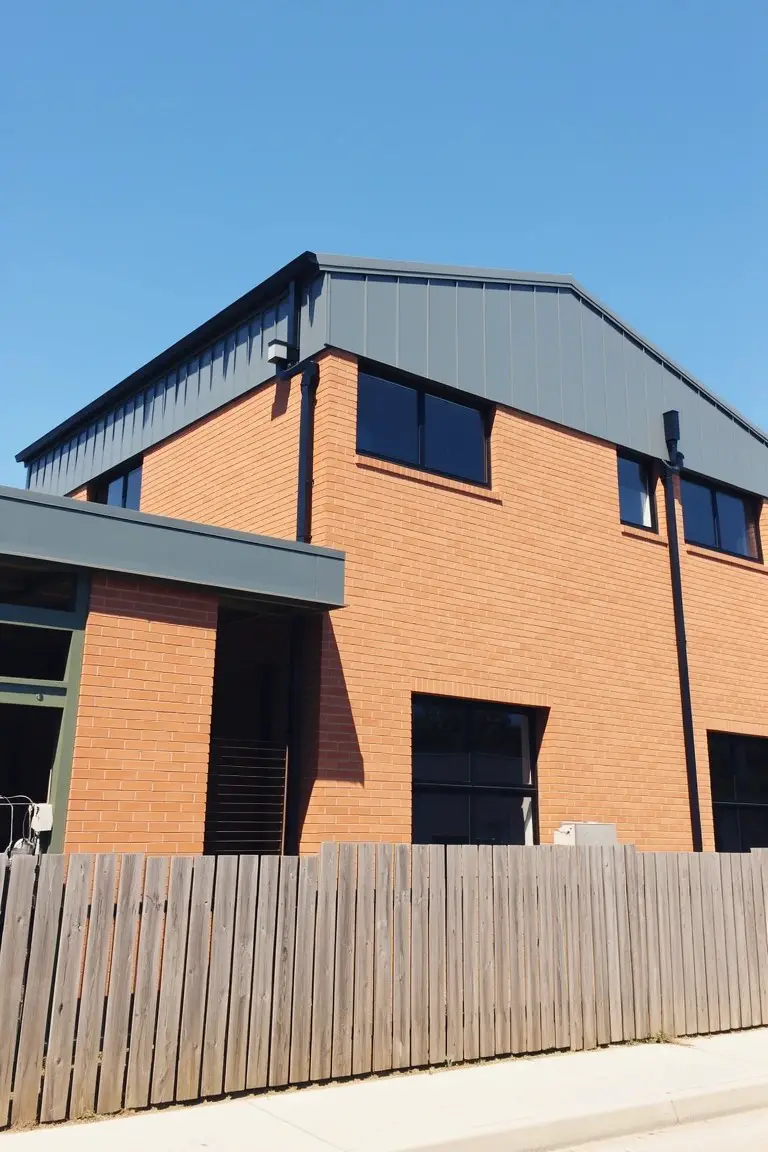 Brick house exterior with cool medium gray metal roof and cladding panels for sharp contrast