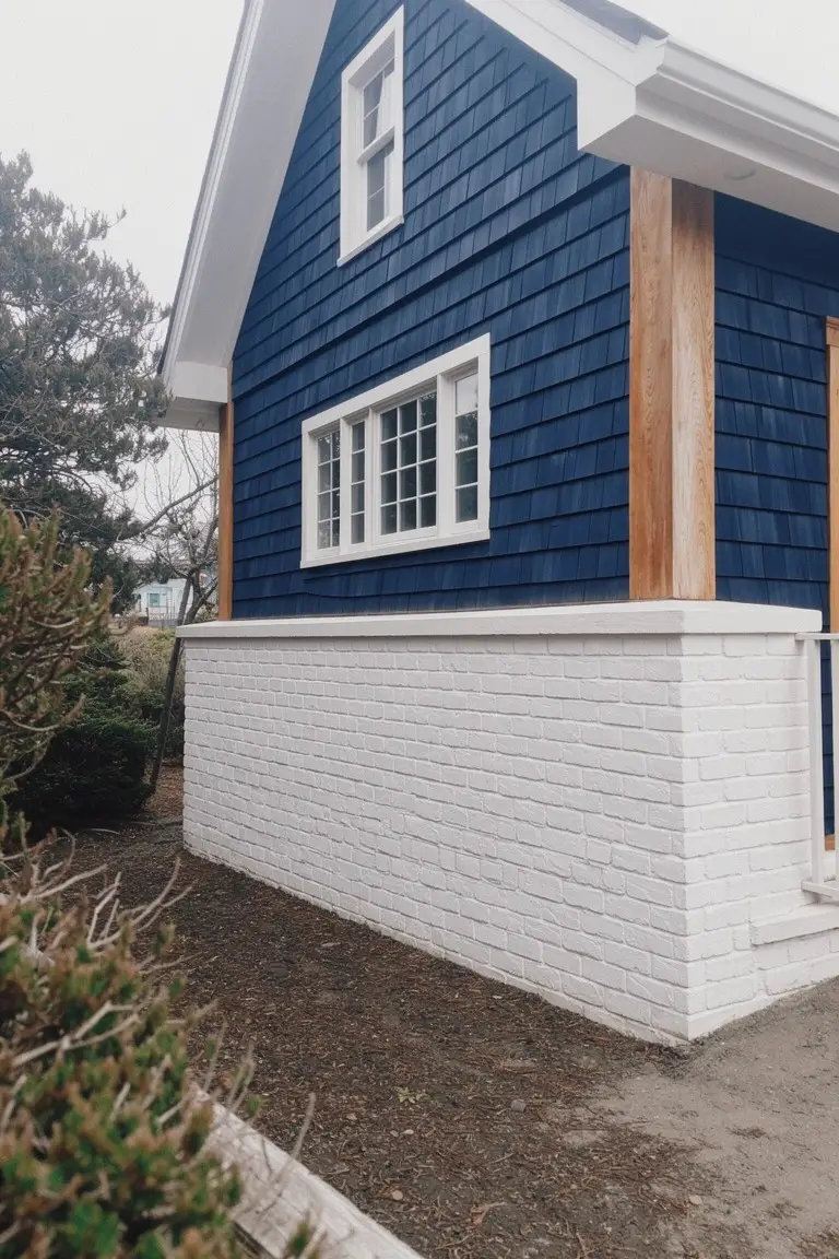 Deep navy blue shingle siding on a house exterior with white brick base and wood trim accents