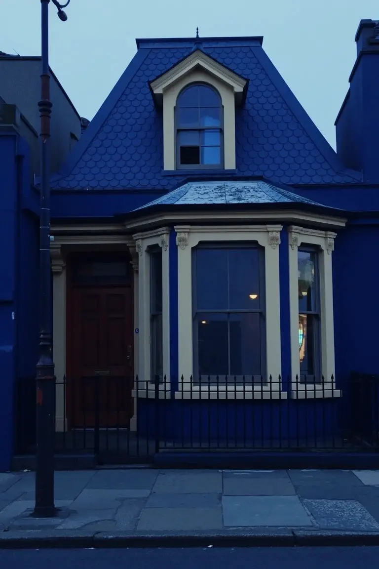 Victorian house exterior in deep navy blue with cream window trim and red front door
