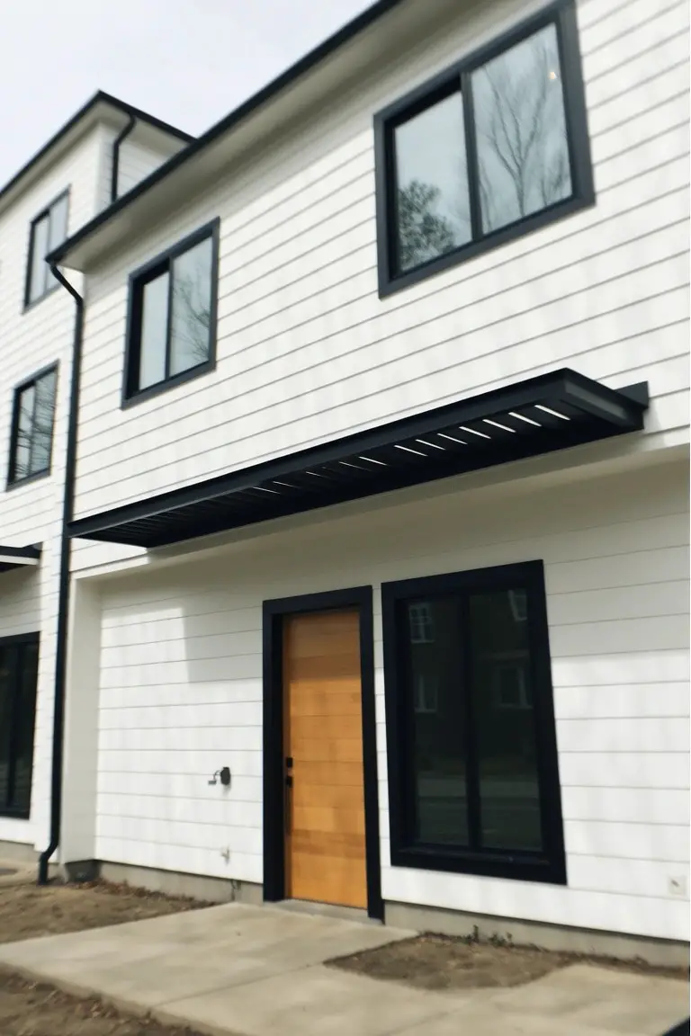 Modern white house with black window trim and warm wood front door