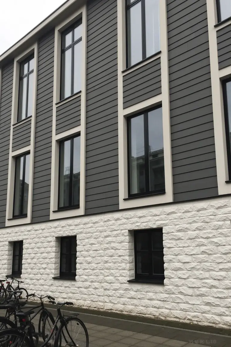 Exterior of modern building with medium cool gray siding over white stone base and large black-framed windows