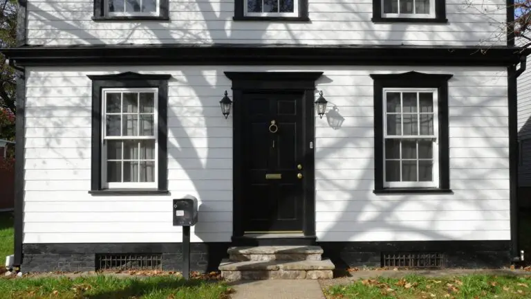 Crisp white clapboard house exterior with black trim, door, and lanterns