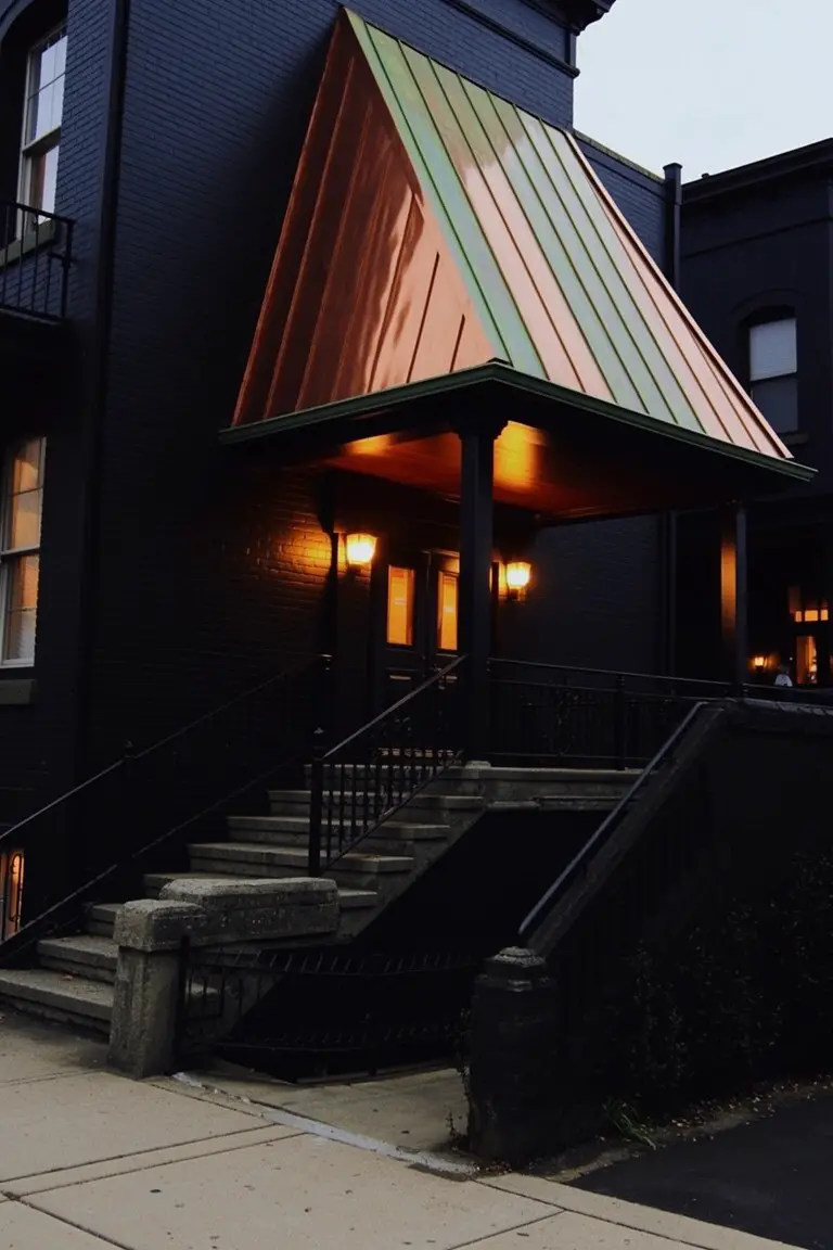 Deep black brick house exterior with copper roof and warm porch lights