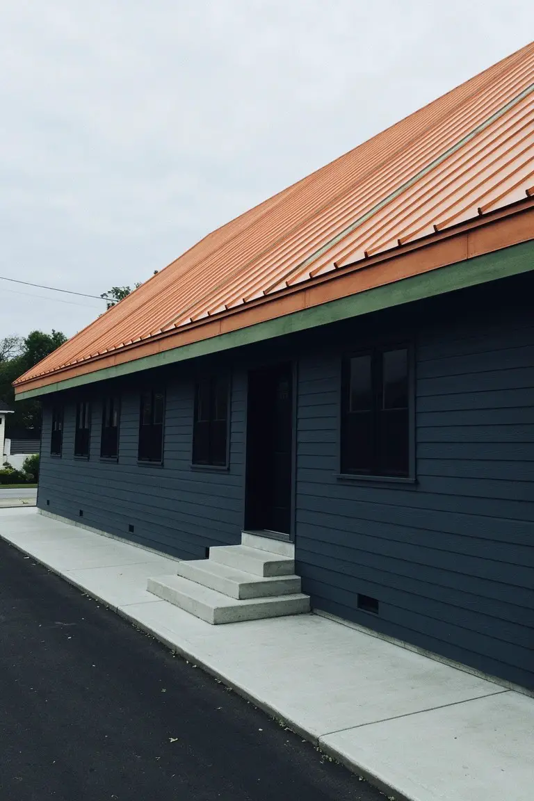 Simple outbuilding with deep navy siding under an orange metal roof