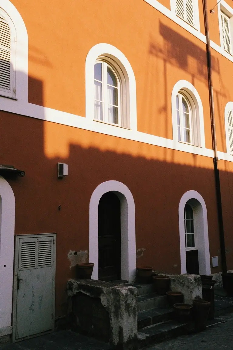 Warm terracotta exterior walls with crisp white arched trim and stone entry steps