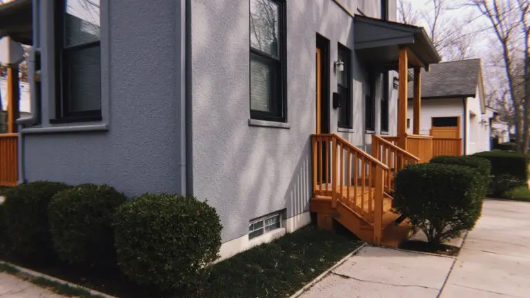 Dark gray stucco house exterior with wooden porch and black-trimmed windows