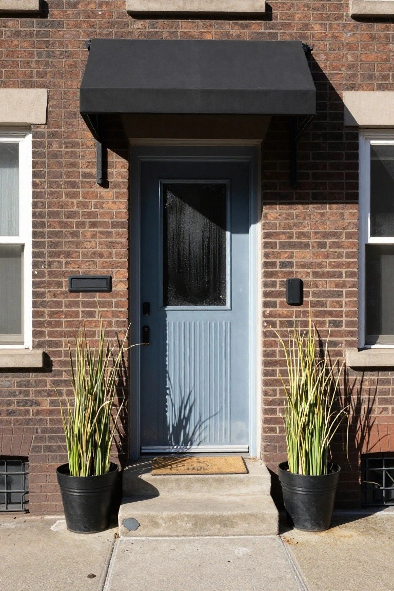 Blue door with glass panel, black awning, and potted plants on either side.