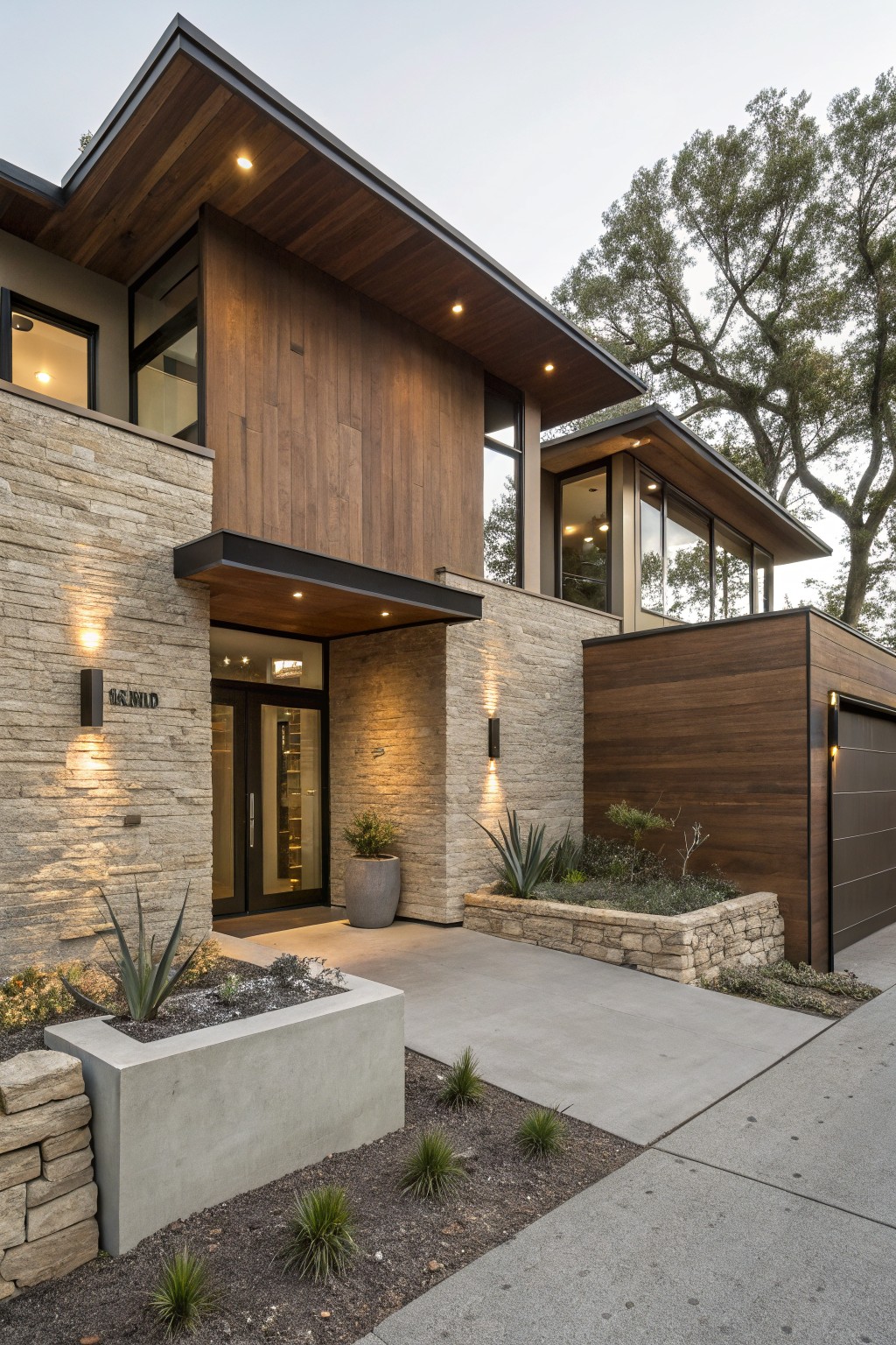 Modern house facade with beige stone lower walls, vertical brown wood cladding on upper sections, black metal entry doors and garage, recessed lighting, and succulent planters by the entrance.