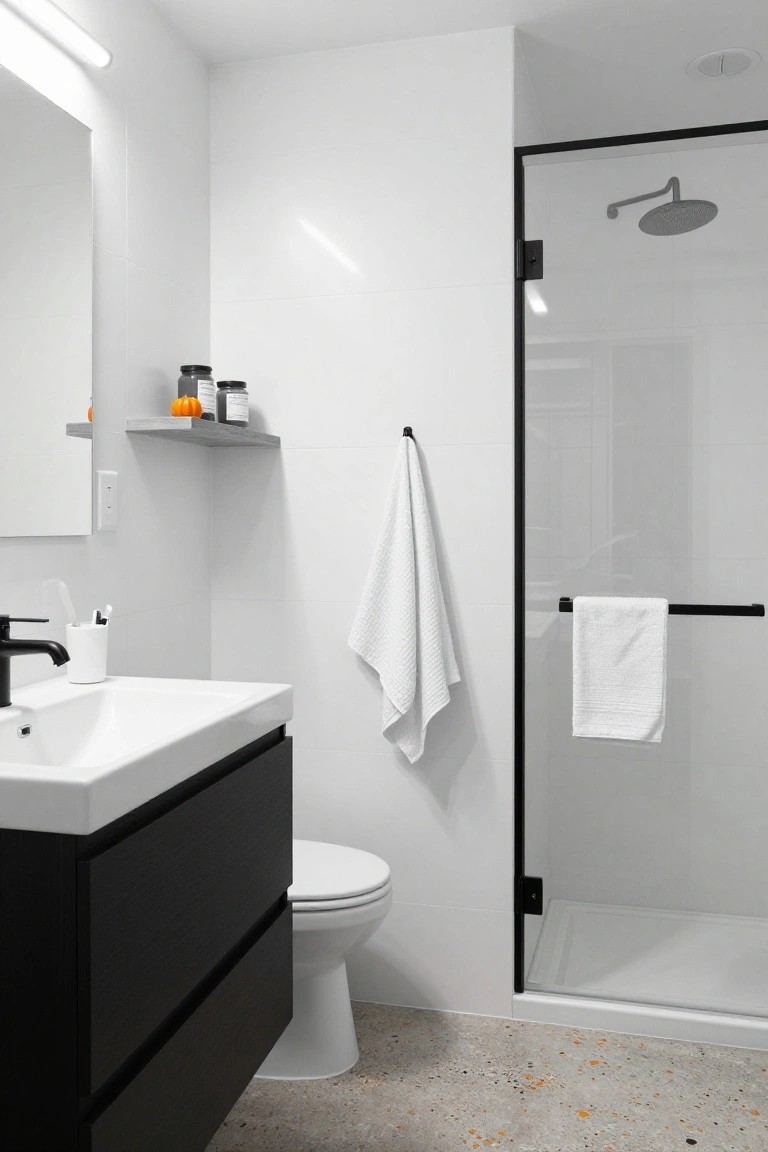 Modern bathroom with light beige tile walls, floating oak vanity with black sink, round backlit mirror, glass shower enclosure with pebble stone floor, and Halloween decor including small orange jack-o'-lantern pumpkins on shelves and a paper star garland near the window.