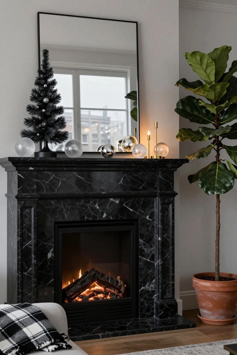 Black marble fireplace with lit gas fire, mantle decorated with small black Christmas tree, clear glass orbs, metallic spheres, and gold candleholders, next to large potted fiddle leaf fig plant and black-framed mirror above sofa.