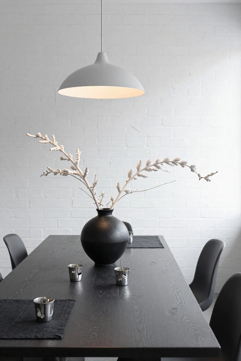 Long formal dining table covered in dark velvet cloth, centered with black calla lilies in a black pot and surrounded by black candles, crystal stemware, white napkins, and silverware.