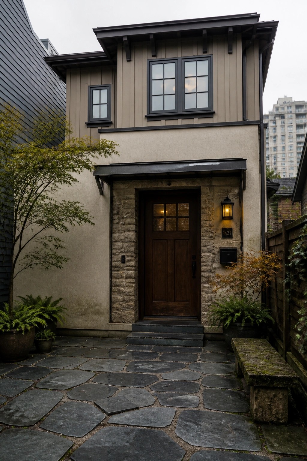 Beige house entrance with dark wood door, stone pathway, and potted ferns