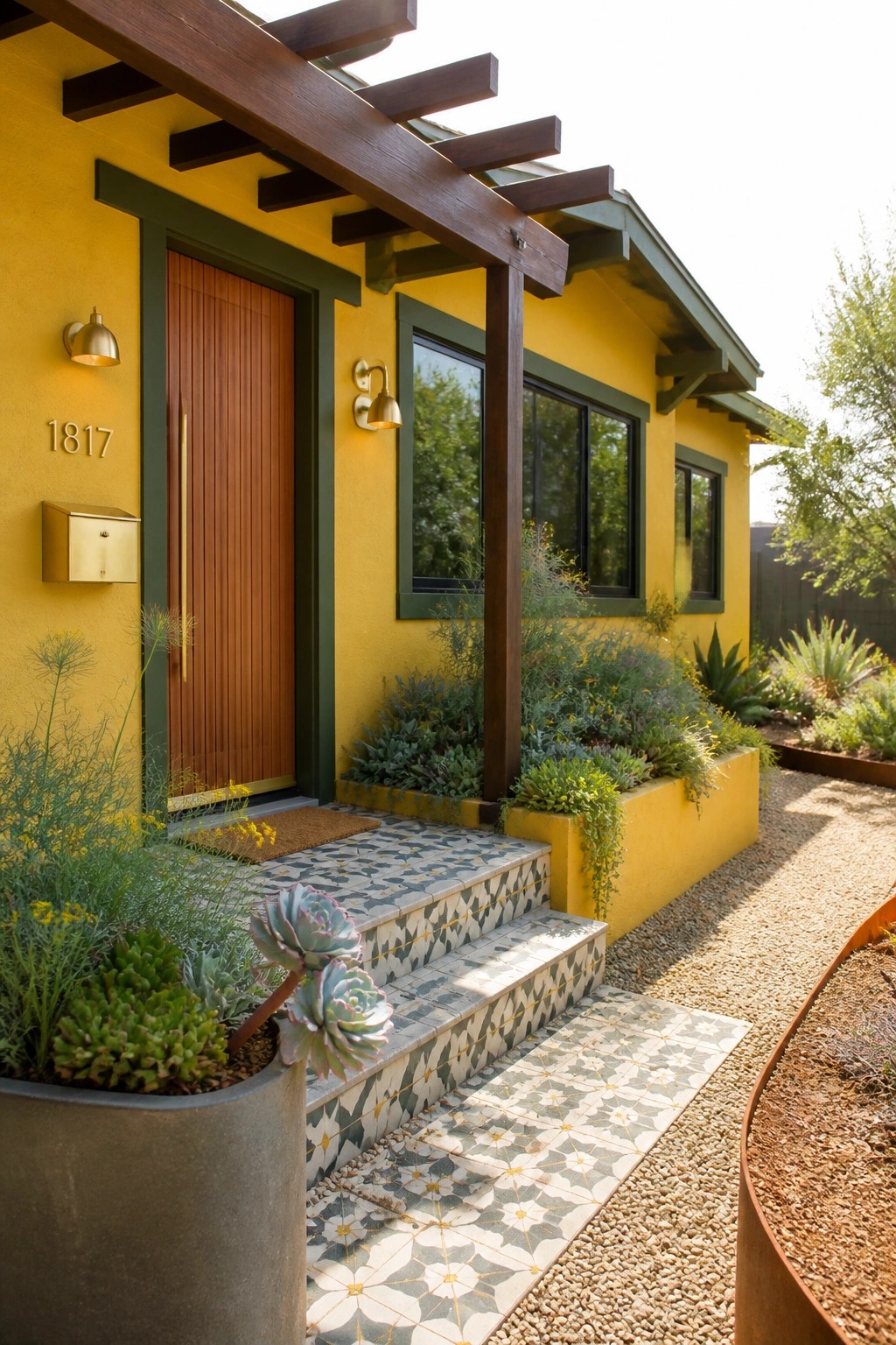 A bright yellow house exterior featuring dark green trim around the door and windows, a vertical wood door, patterned tile steps, and surrounding plants.