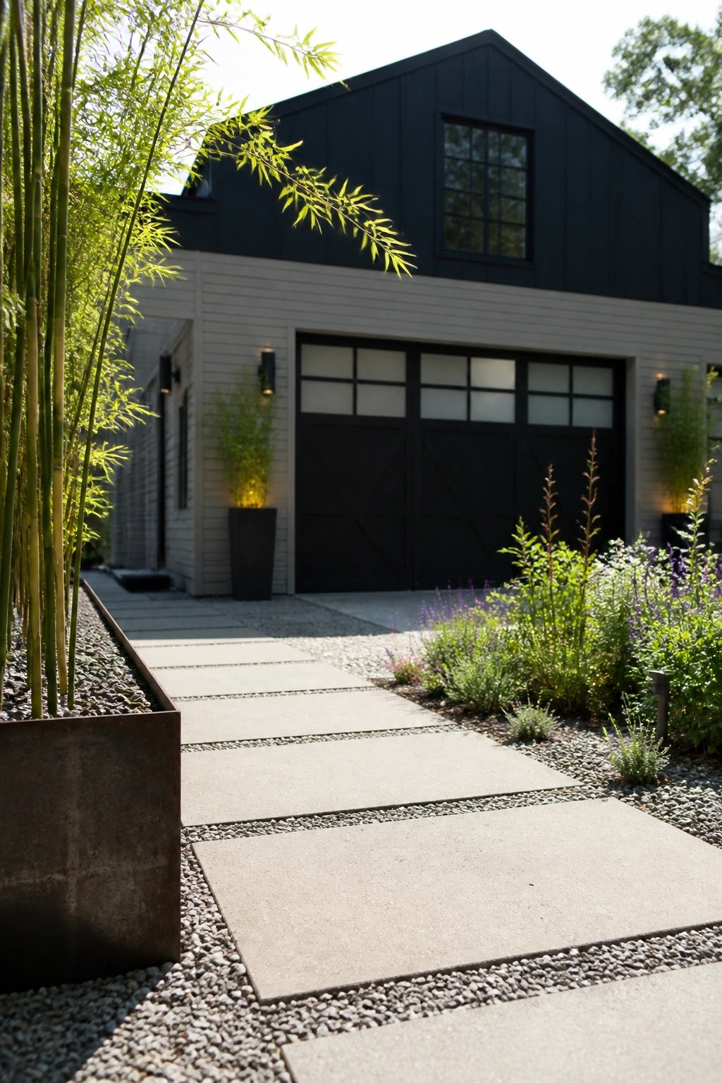 A modern house exterior with black upper gable and garage door set against light gray siding, with a concrete path, gravel, and tall bamboo plants in the foreground.