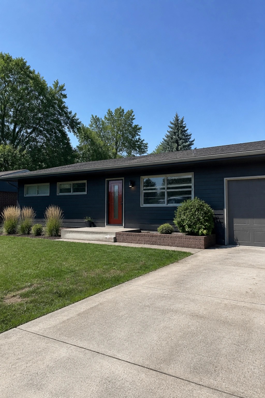 Dark blue single-story house with red door, gray garage, and green lawn