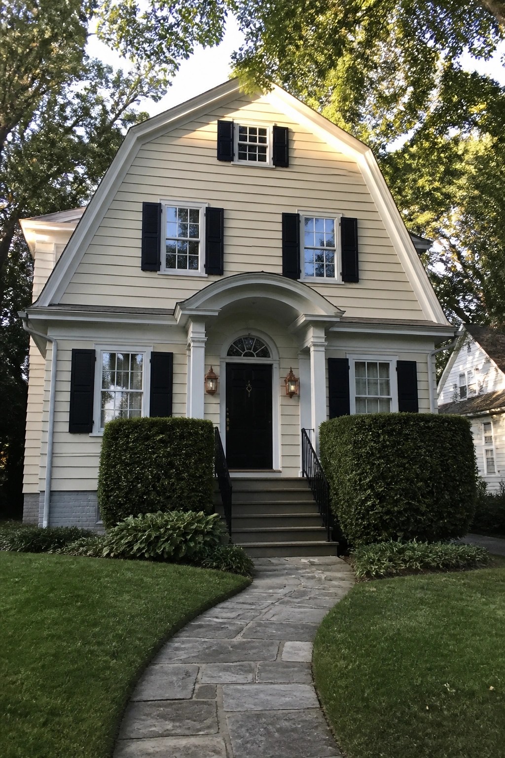 A traditional house exterior with warm cream vinyl siding and white trim.