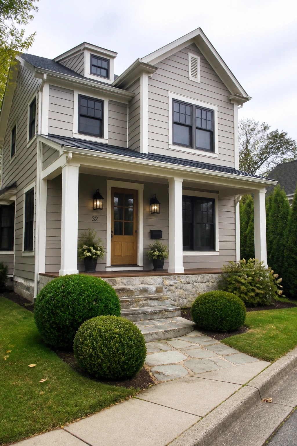 Light greige vinyl siding on a two-story house with white trim and a stone foundation.
