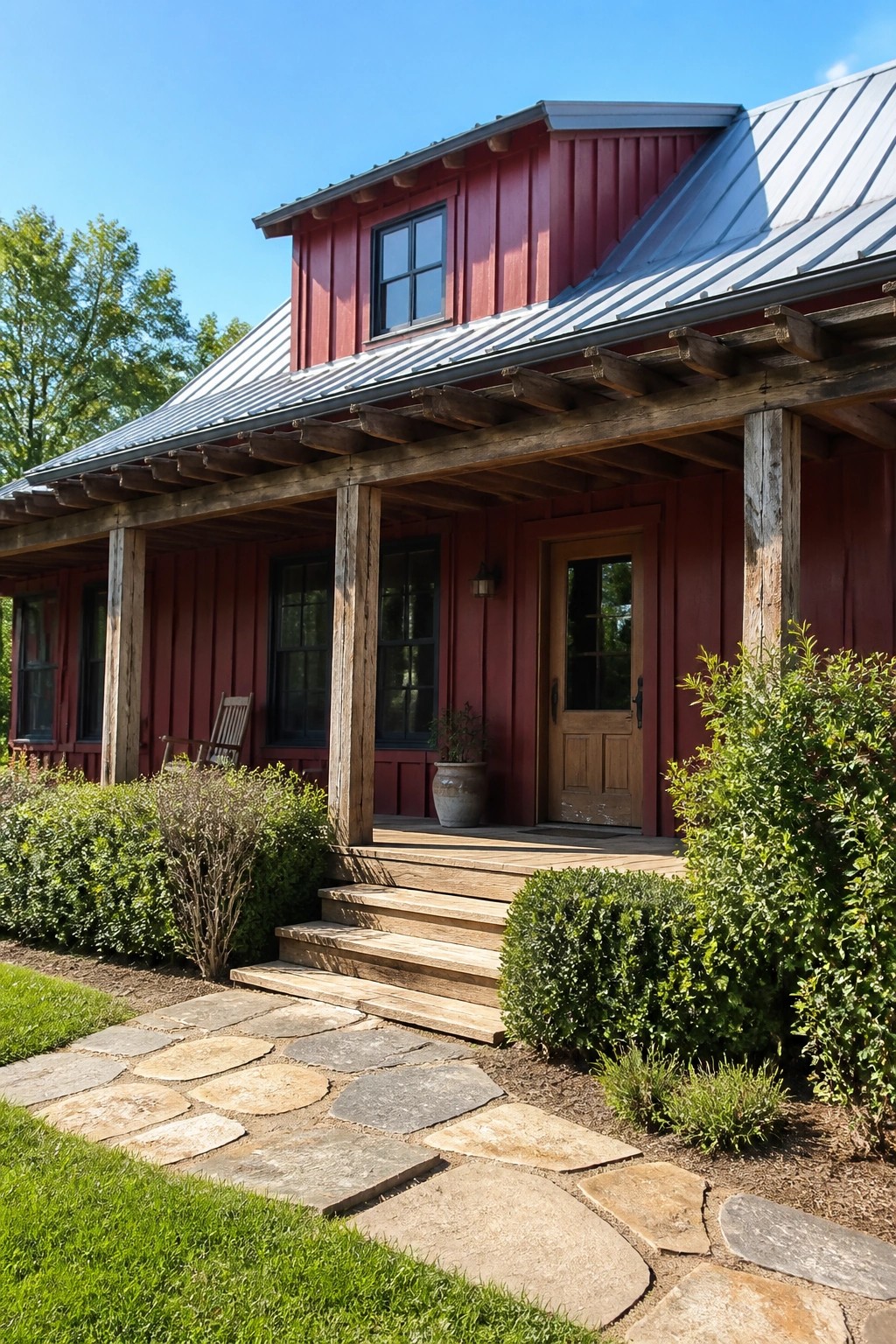Red wooden house with metal roof, porch, steps, stone path and greenery