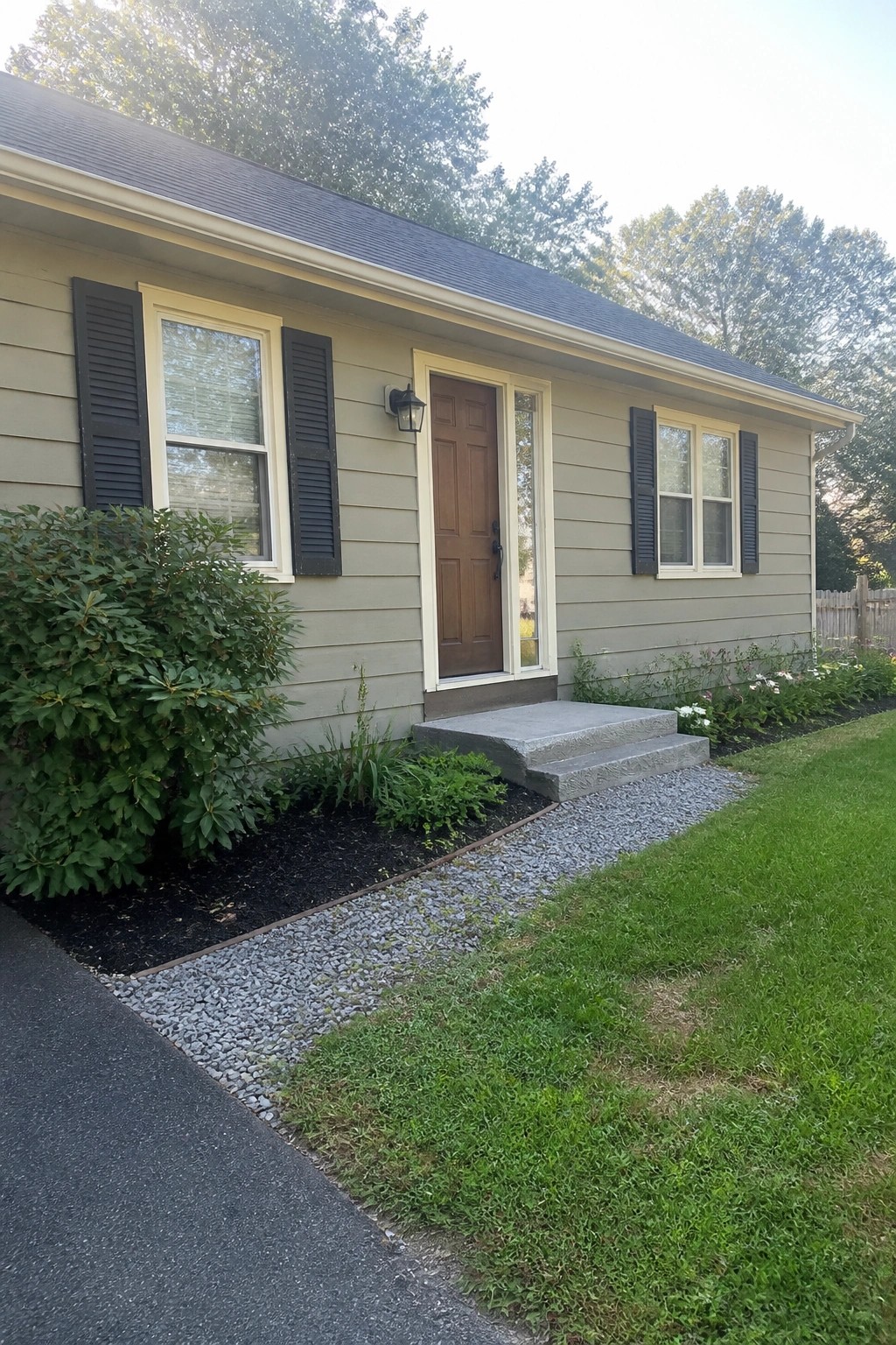 Light greige beige siding on a suburban house with concrete steps and a wood door.