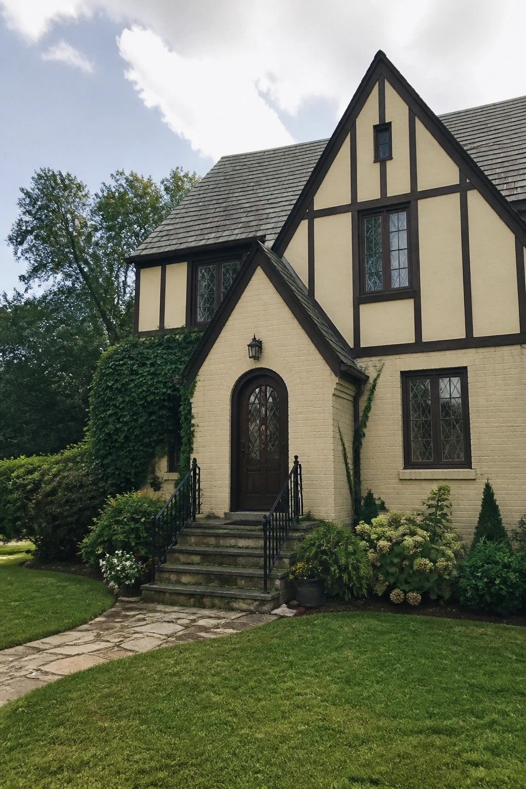 Beige Tudor-style house exterior with dark brown half-timbering and brick base.