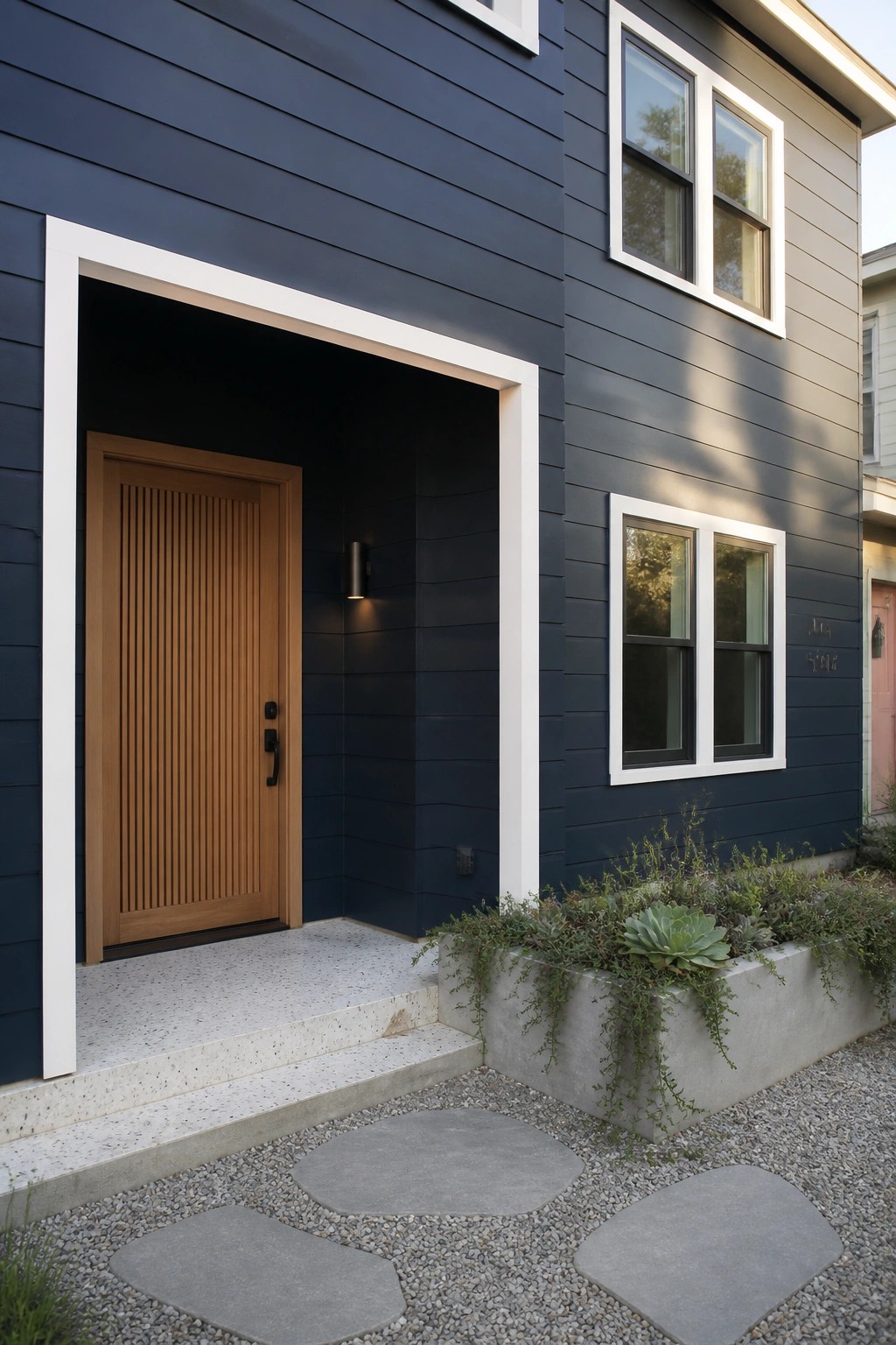 Dark navy blue siding on a modern house exterior with white trim and a wood entry door.