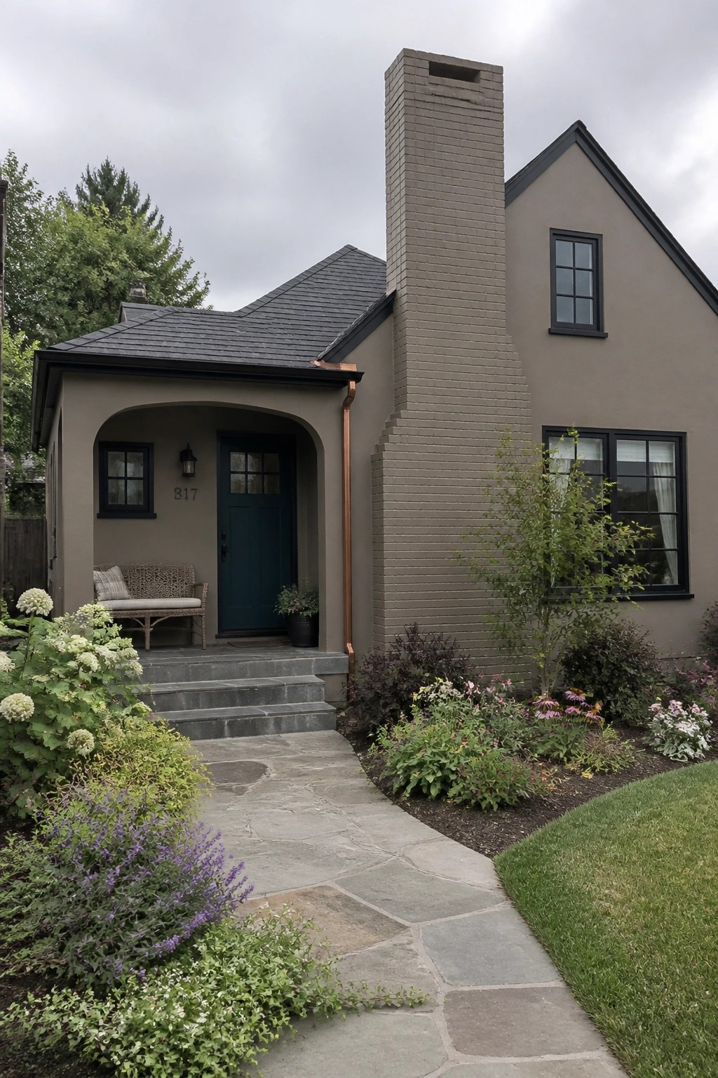 Beige house with arched porch, dark green door, brick chimney, and stone path.