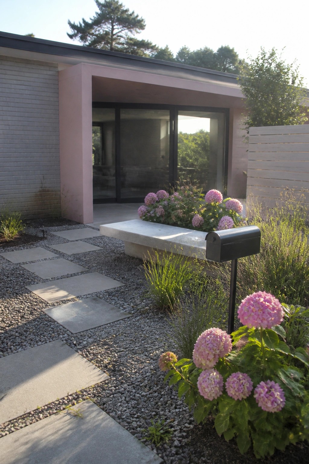 A modern house exterior featuring pink structural accents, gray brick walls, large glass doors, concrete stepping stones set in gravel, and clusters of pink hydrangeas near a black mailbox.