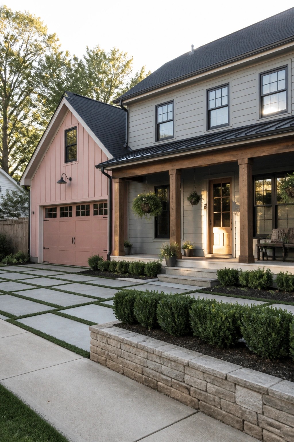 A house exterior showing gray siding on the main structure and soft pink siding on the attached garage, with a wooden porch, steps, and stone retaining wall in front.