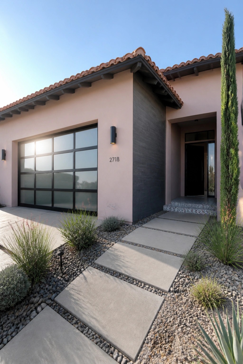 Modern pink stucco house with terracotta roof, glass garage, and concrete paver path.