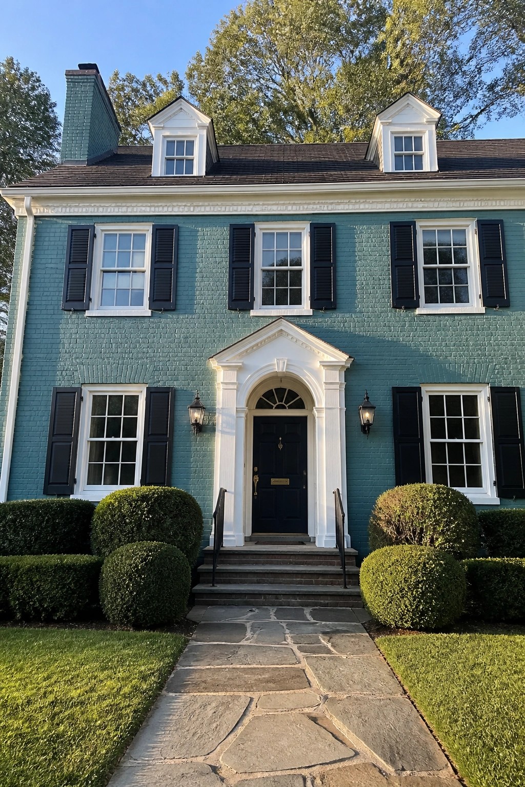 A two-story brick house painted in bold teal with white trim and black shutters.