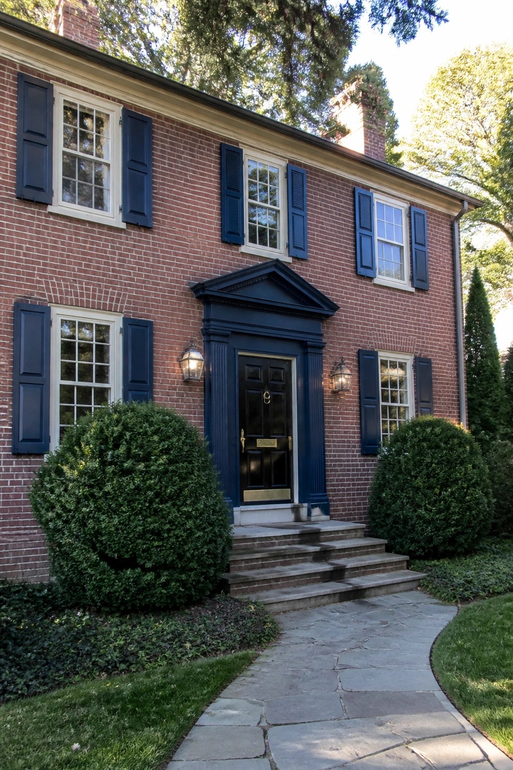 A red brick house with a deep navy door and trim around the entry.