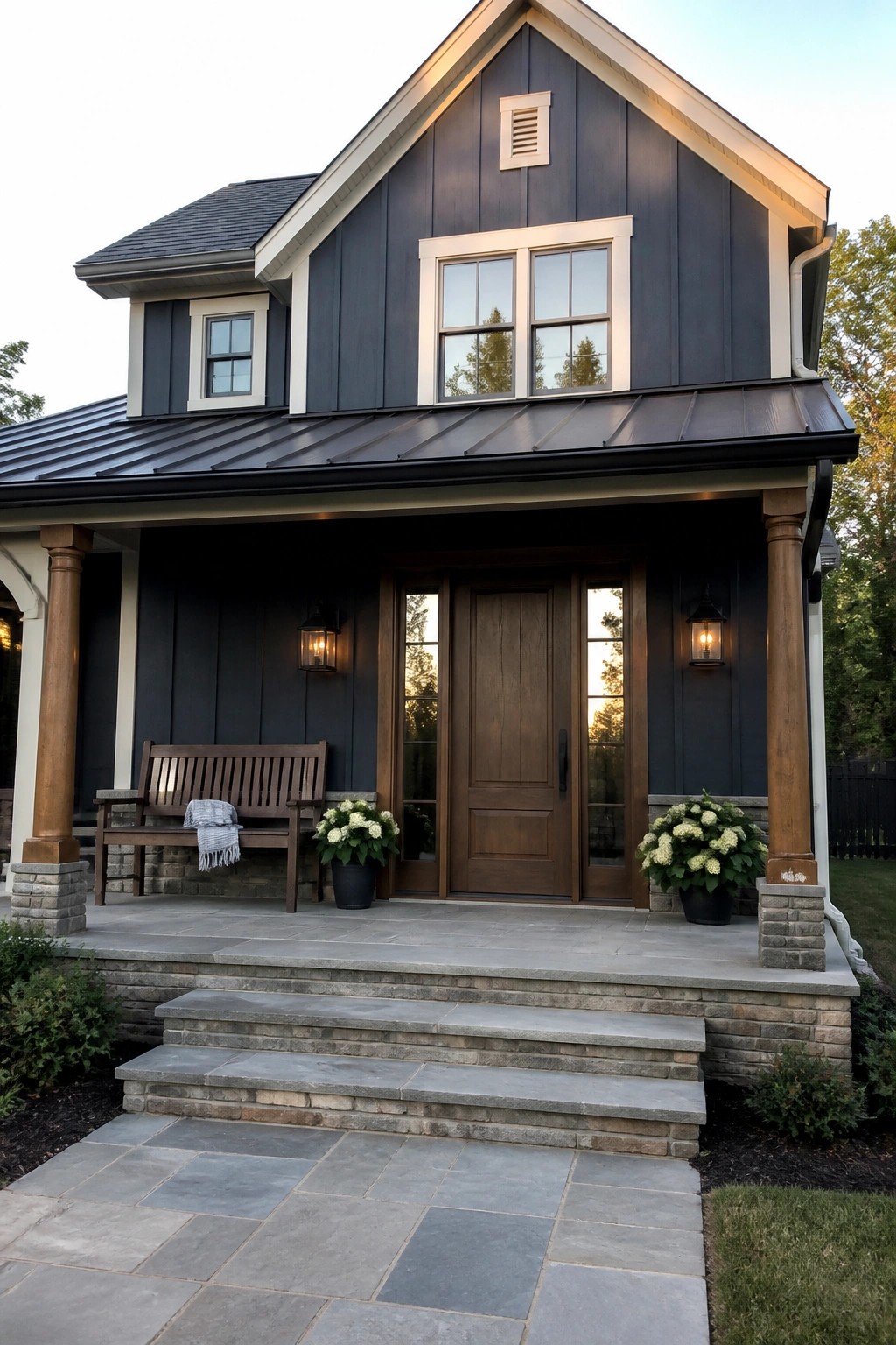 Dark gray house with wooden porch, bench, double doors, potted flowers, and stone steps.