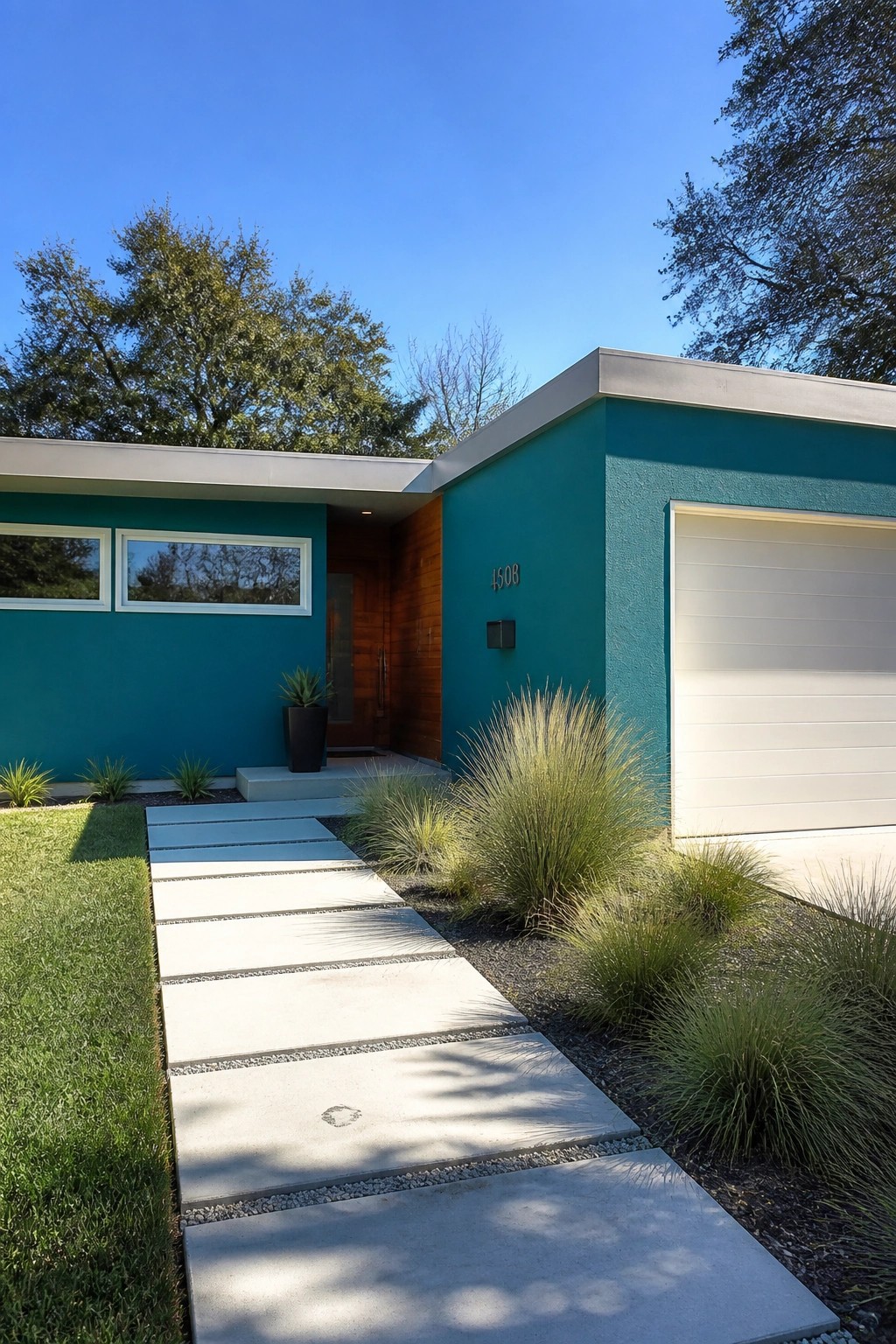 Modern house exterior painted in a bold teal color with white garage door and wood accents.