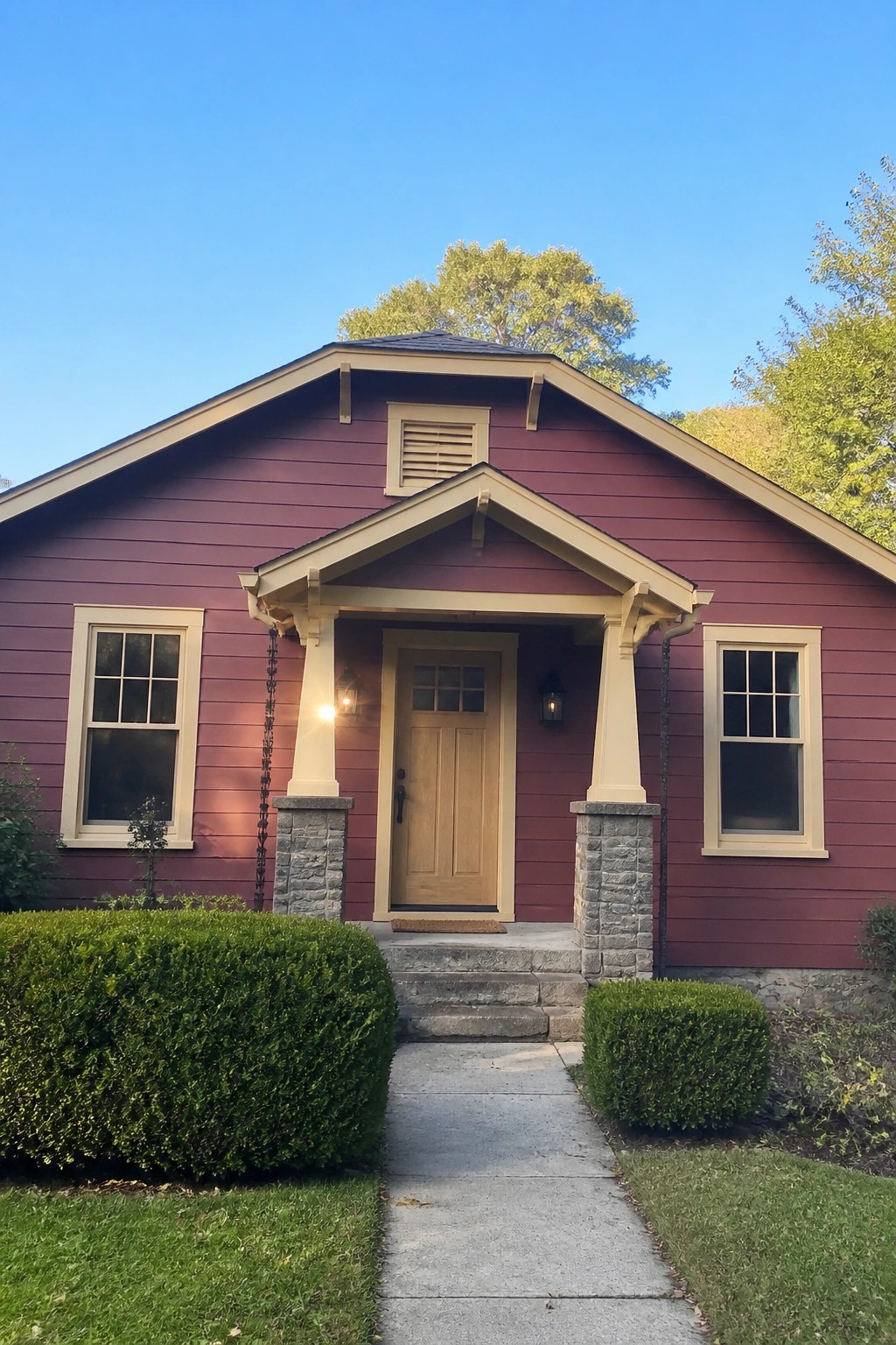 A small cottage with deep red siding, cream trim, and a stone porch.