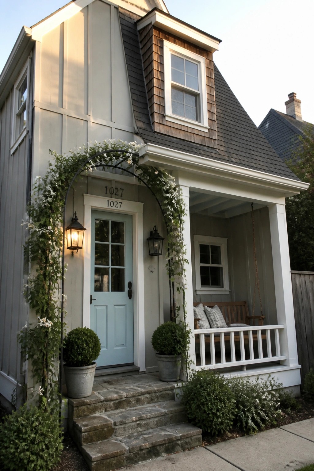 Small cottage exterior with light gray siding and a dark shingled roof.