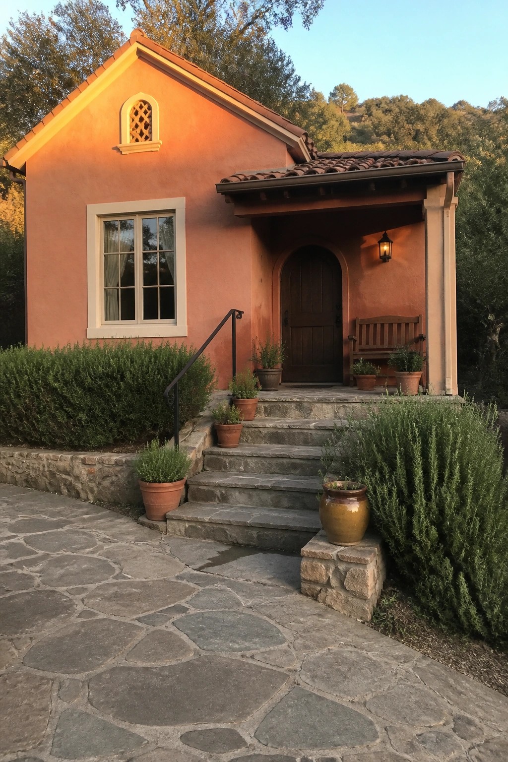 A small cottage exterior painted in warm terracotta stucco with stone steps and a tiled roof.