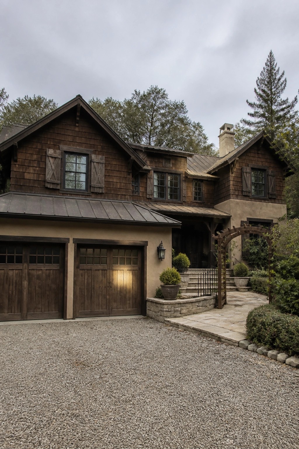 Rustic dark wood house with two garage doors on gravel driveway and garden path