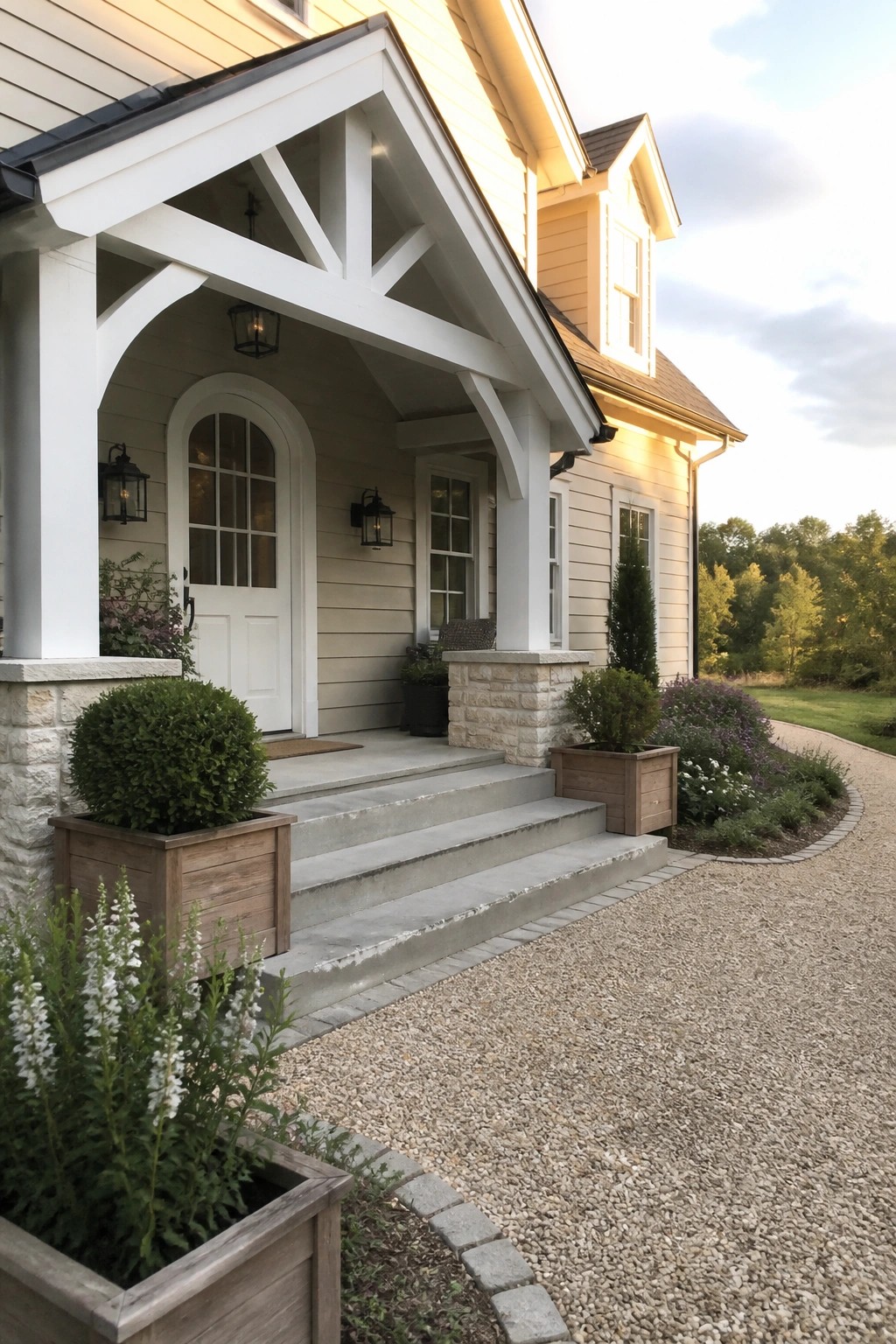 Yellow house porch with white trim, arched door, concrete steps, and wooden planters.
