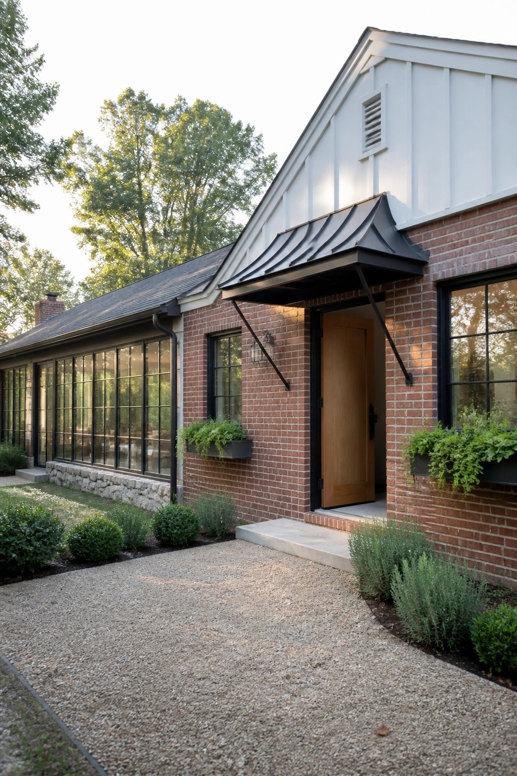Red brick house with black metal awning, wooden door, and green window boxes.