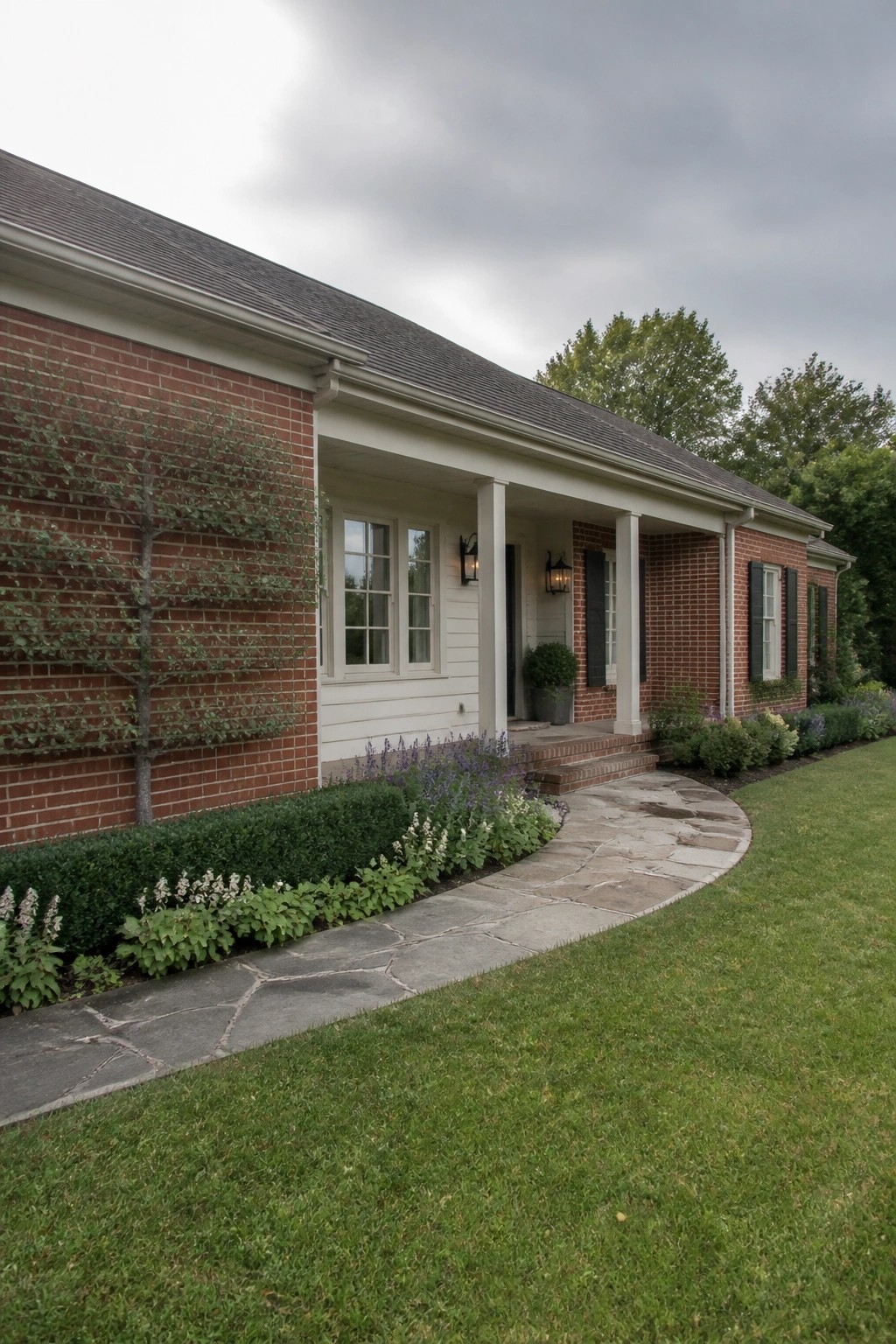 Red brick house with white porch, black shutters, stone path and lawn.