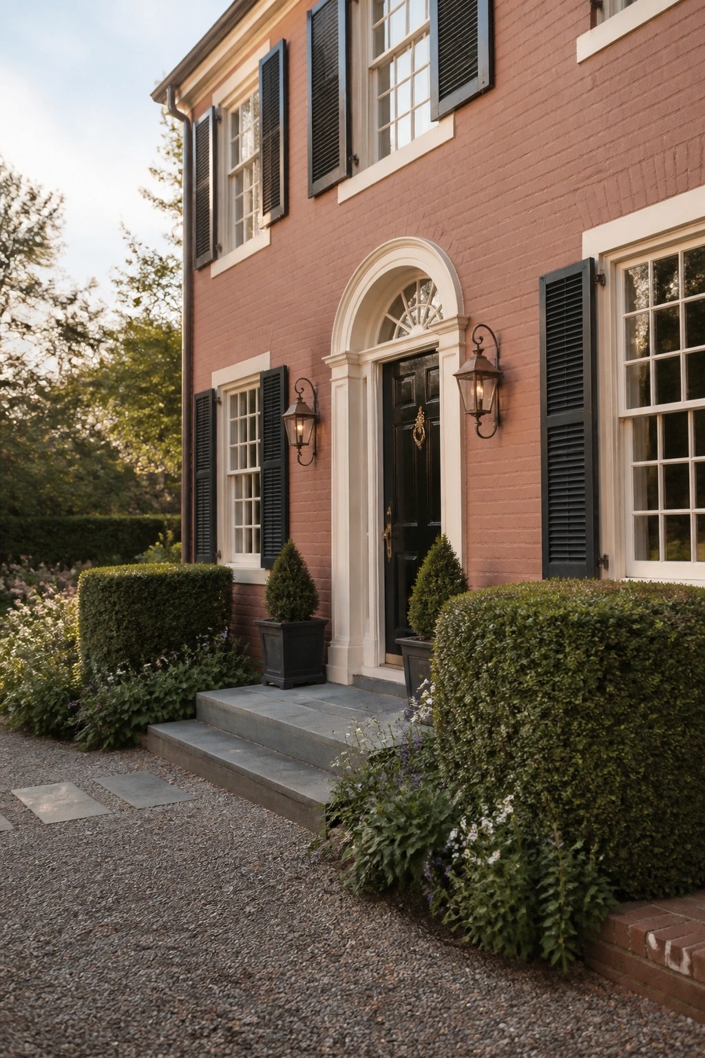 Colonial brick house painted in a soft red tone with white trim and black shutters.