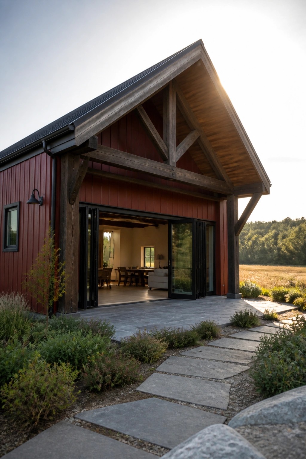Modern red barn house with open glass doors, wooden beams, and stone pathway.