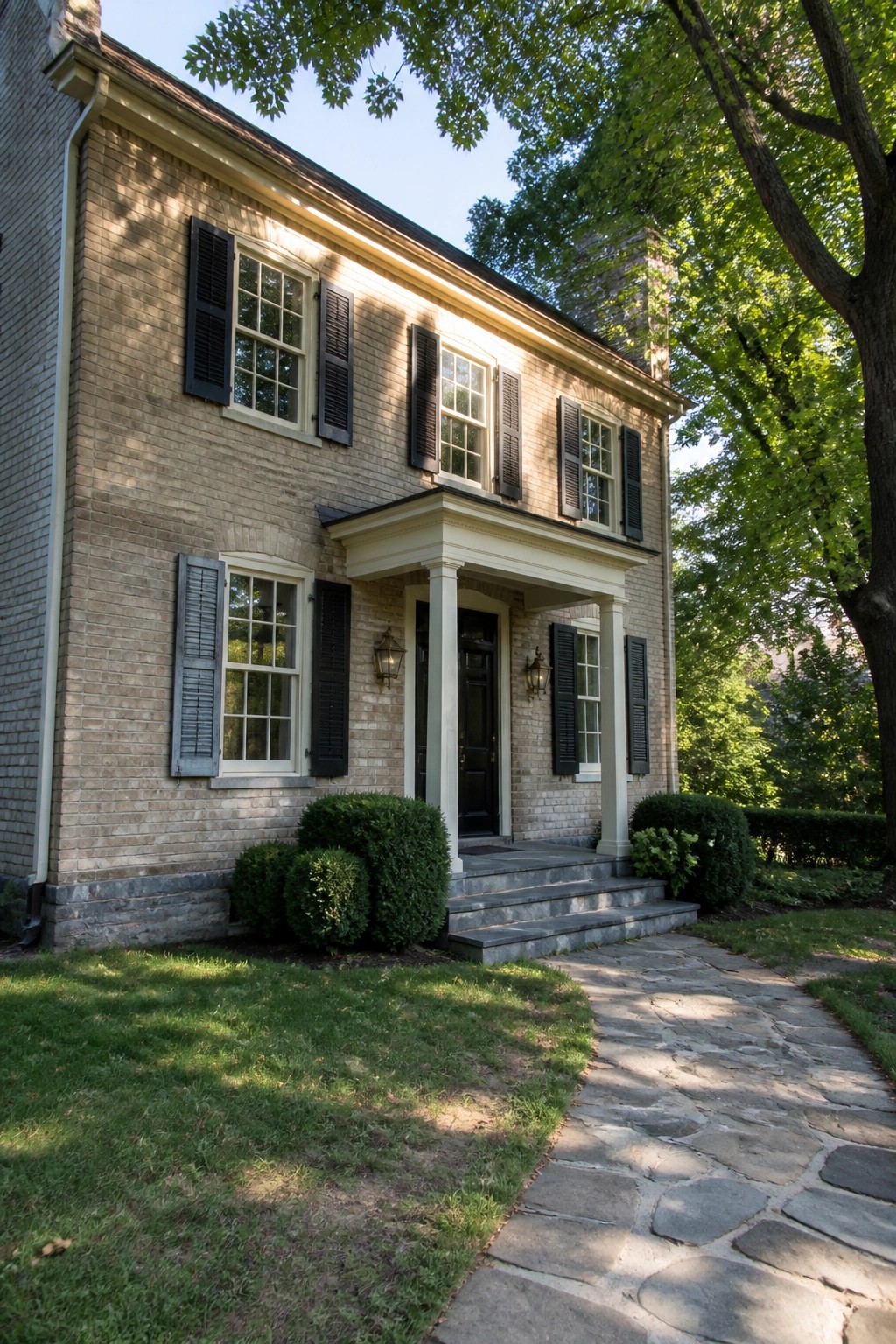 A two-story brick house painted warm beige with white trim and a stone foundation.