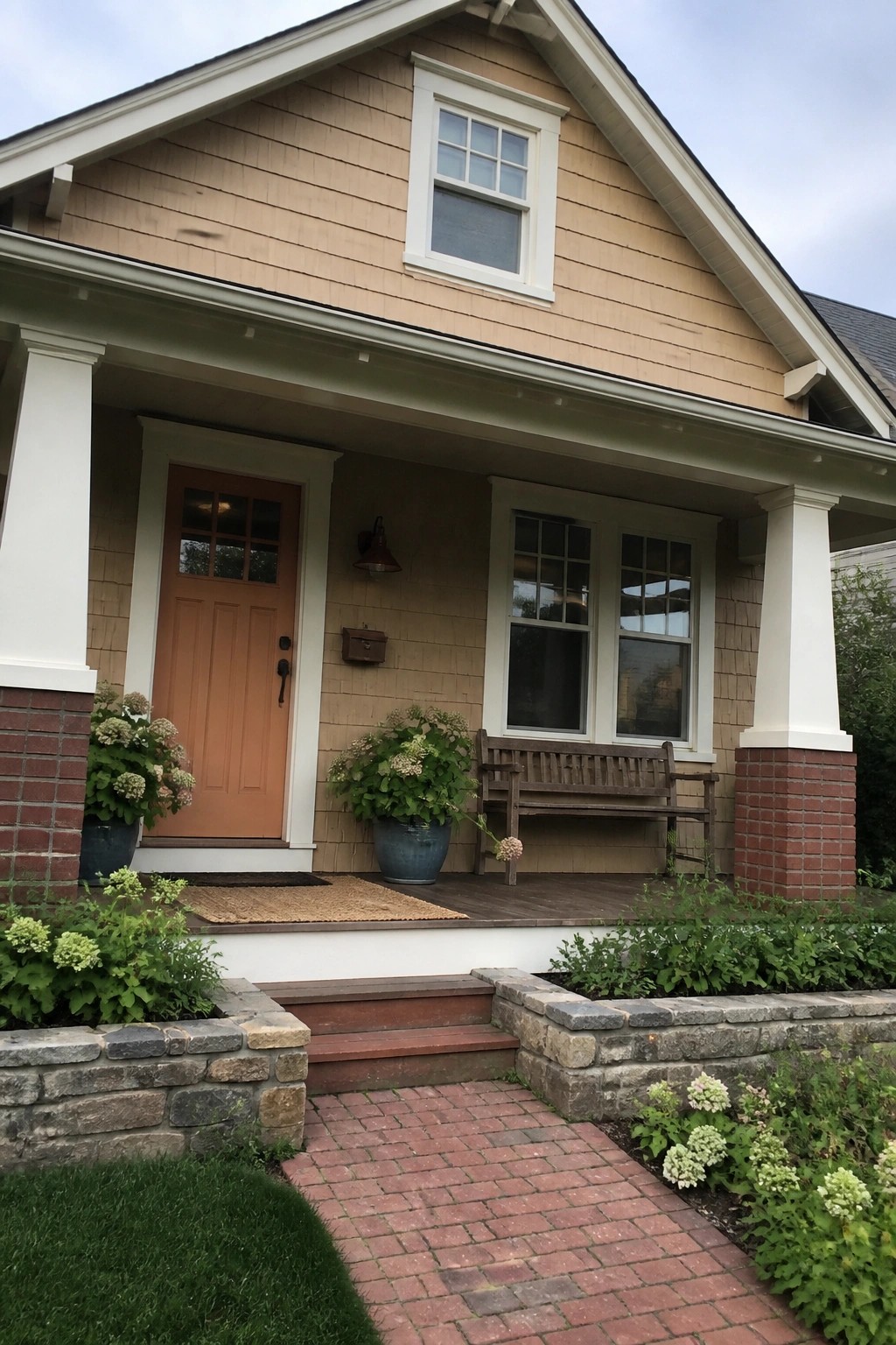 Light warm beige house siding with red brick porch columns and white trim.