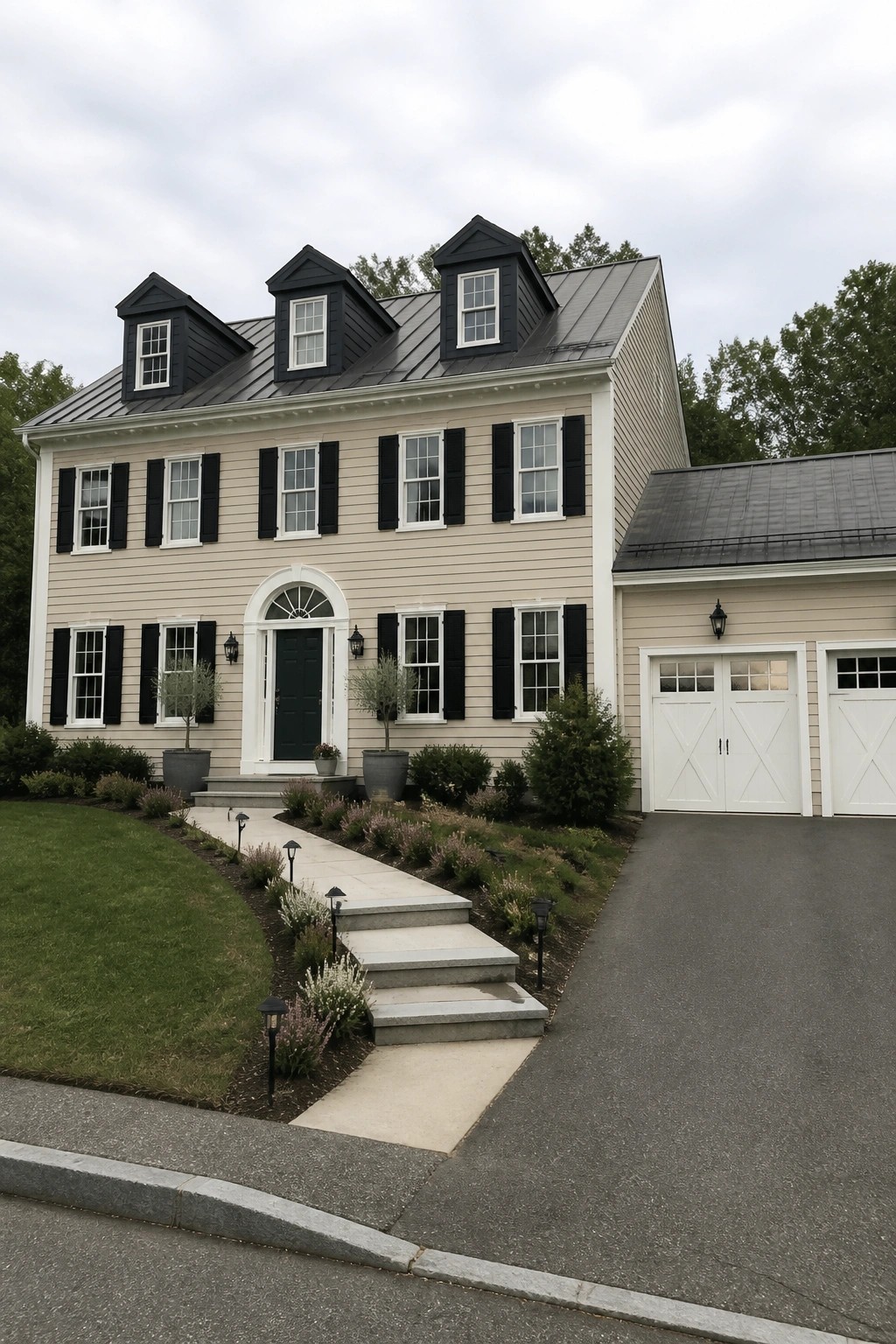 A two-story suburban house with beige siding, black shutters, a dark metal roof with dormers, and an attached garage with white doors.
